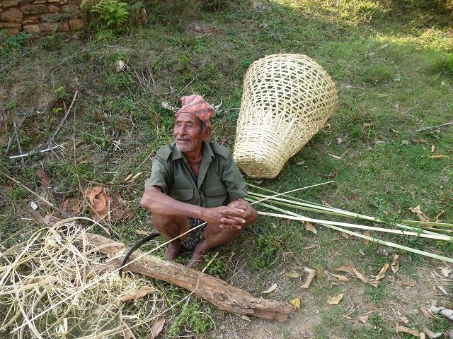 Alter Mann bearbeitet mit der Sichel einen Bambus für einen Tragekorb